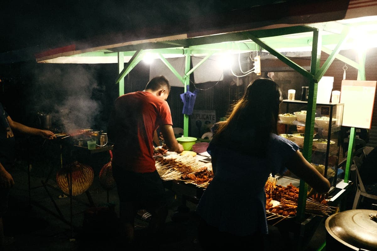 A person grilling over an open flame at dusk